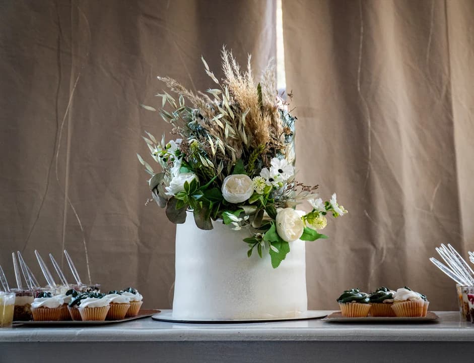 Torta de boda con arreglo floral y cupcakes