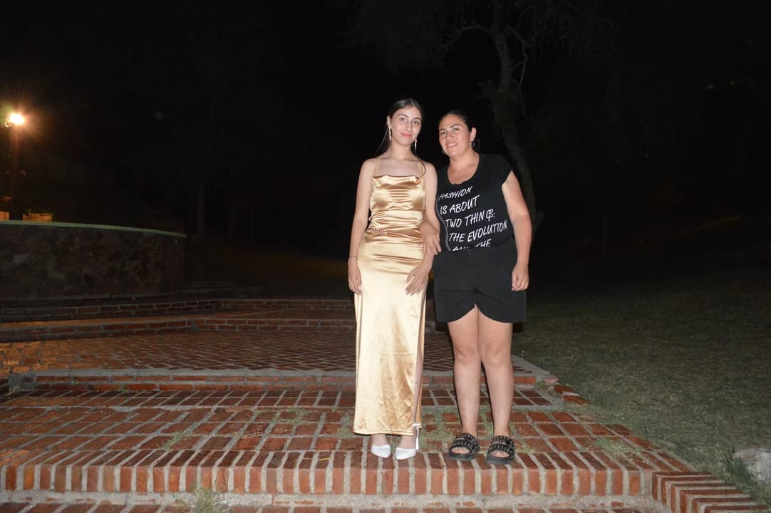 Egresada con vestido dorado posando con amiga en explanada