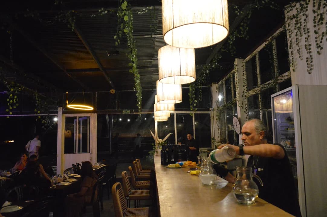 Bartender sirviendo en la barra con lámparas colgantes