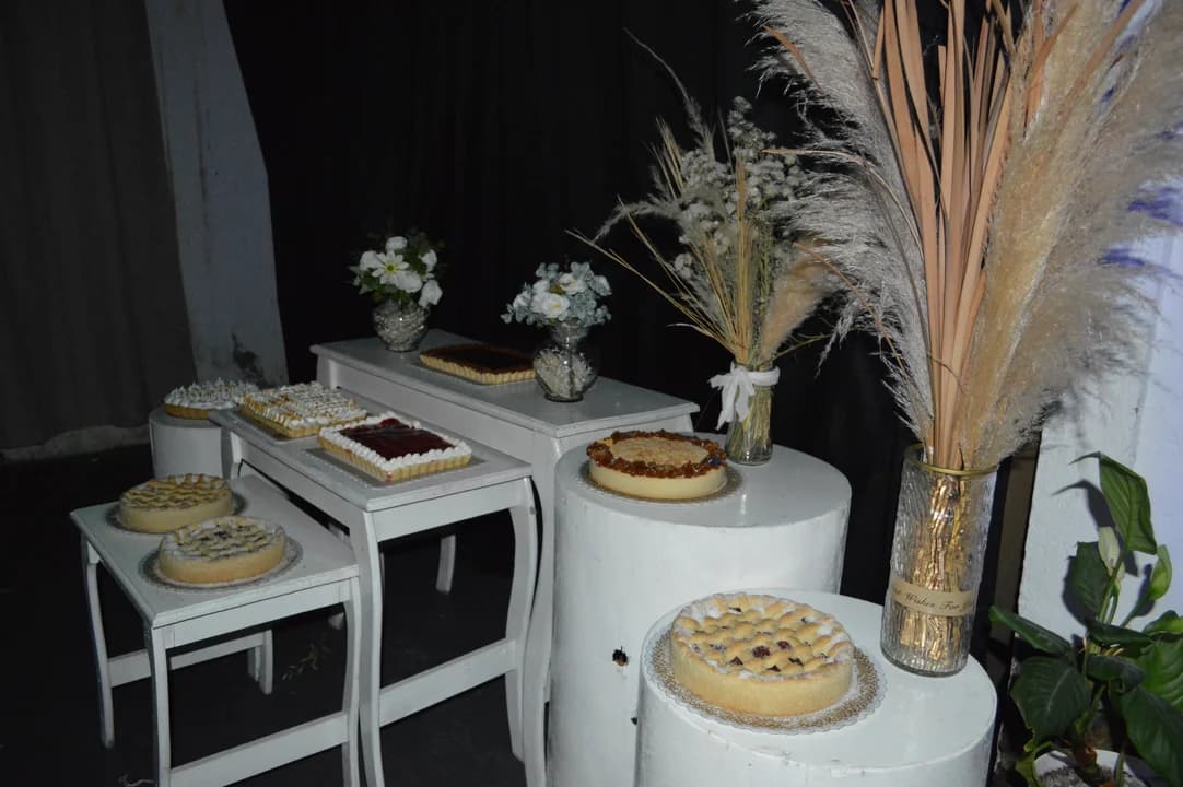 Mesa dulce elegante con tartas y pampas en pedestales blancos