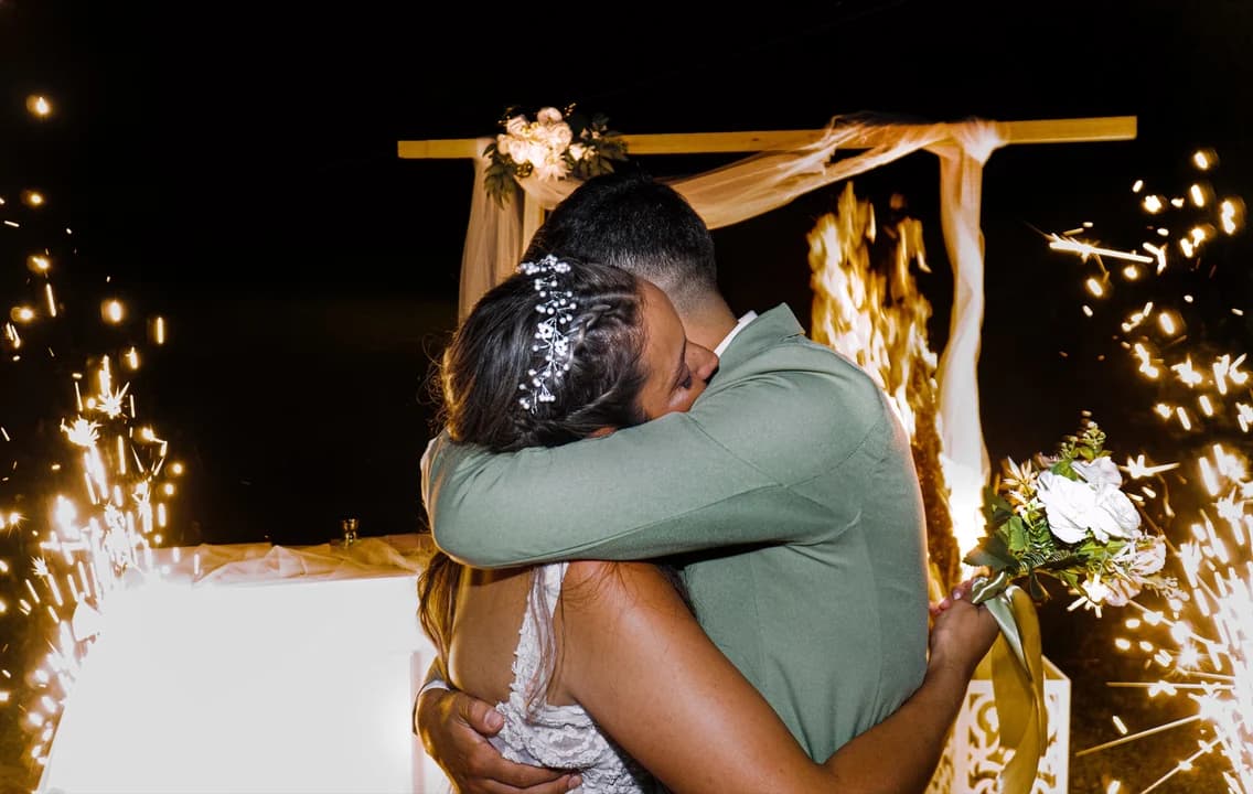 Abrazo íntimo de novios con bengalas de fondo