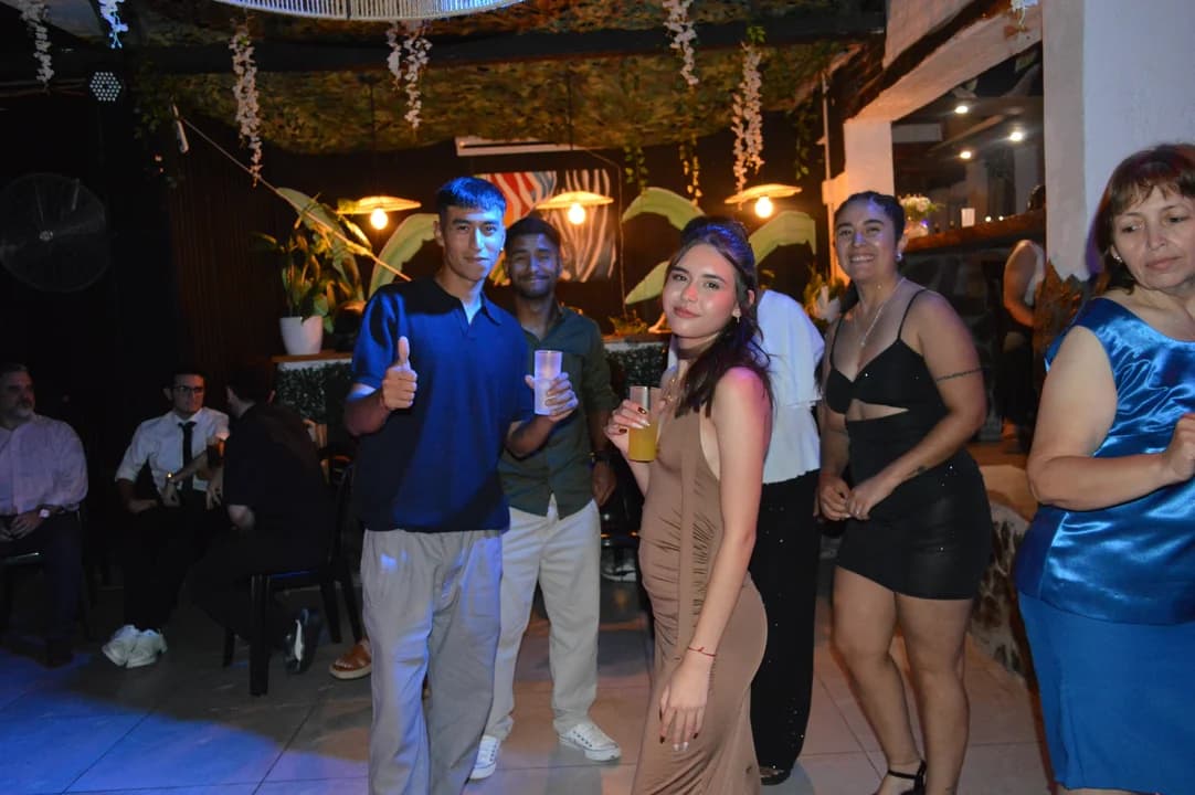 Jóvenes posando en la fiesta con decoración tropical y luces